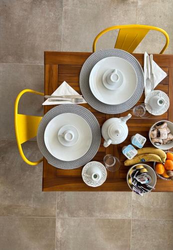 a table with white plates and dishes on a yellow chair at La casa di Pippo Flora in Agrigento