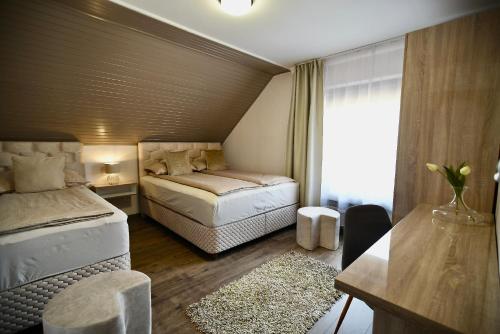 a bedroom with two beds and a desk and a window at Crystal Apartman in Mórahalom