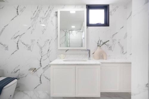 une salle de bain blanche avec un lavabo et un miroir dans l'établissement MIQ Ekkamai3_Pool Villa_3BR house, à Bangkok