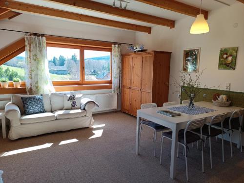 a living room with a couch and a table at Srub Javorná - apartmány Šumava in Javorná