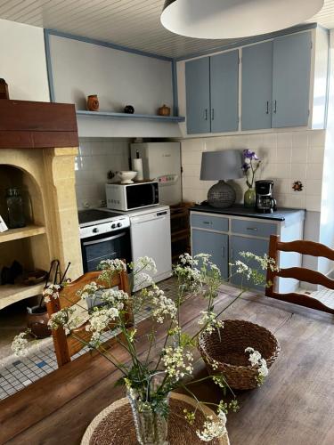 a kitchen with blue cabinets and a table with flowers at Maison de famille chaleureuse in Bassillac
