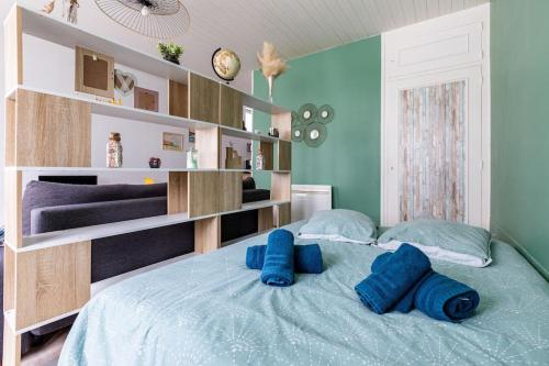 ein Schlafzimmer mit einem Bett mit blauen Kissen darauf in der Unterkunft Studio Au coeur de la baie in Berck-sur-Mer