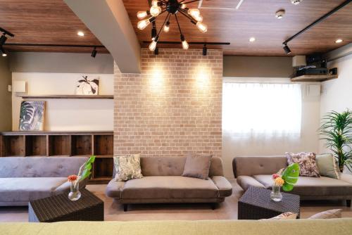 a living room with two couches and a brick wall at LN15 RICCA 三宮5分! 屋上バーベキュー可能!キッチン付パーティ向コンド roof top BBQ in Kobe