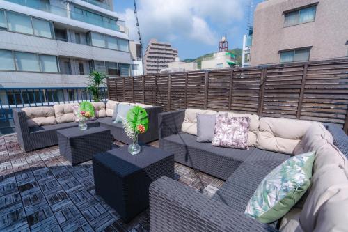 a patio with couches and tables on a rooftop at LN15 RICCA 三宮5分! 屋上バーベキュー可能!キッチン付パーティ向コンド roof top BBQ in Kobe