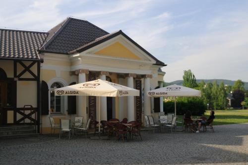 a building with tables and chairs and umbrellas at Chata lázně Evženie Klášterec nad Ohří in Klášterec nad Ohří