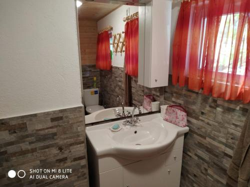 a bathroom with a sink and a toilet and red curtains at Chata lázně Evženie Klášterec nad Ohří in Klášterec nad Ohří