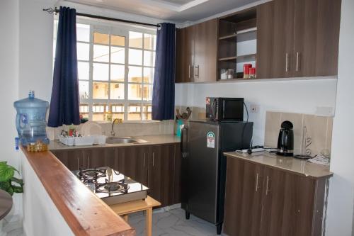 a kitchen with wooden cabinets and a black refrigerator at One bedroom unit with wi-fi & parking in Nanyuki