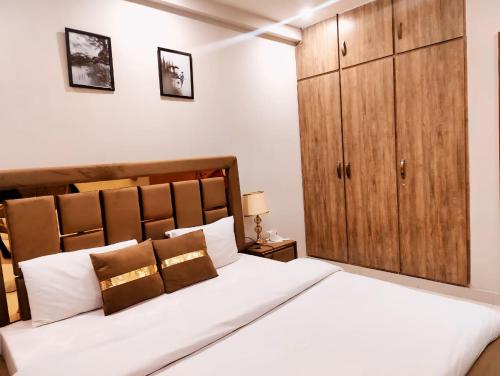 1 dormitorio con 1 cama blanca grande y armario de madera en Morbex Guest House Islamabad, en Islamabad
