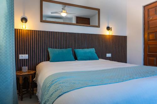 - une chambre avec un lit doté d'oreillers bleus et d'un miroir dans l'établissement Nice cozy townhouse with views, à Mijas
