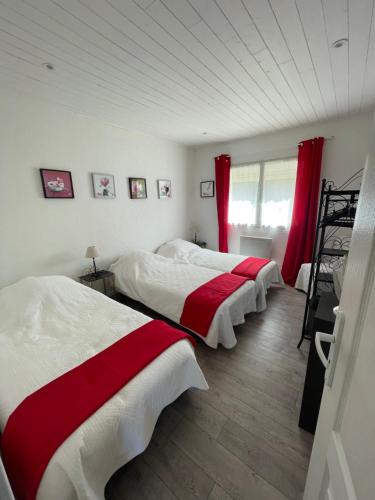 2 camas en una habitación con cortinas rojas en Gaspard, en Monprimblanc