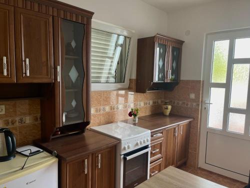 a kitchen with wooden cabinets and a white stove top oven at Kuća Radović in Budva