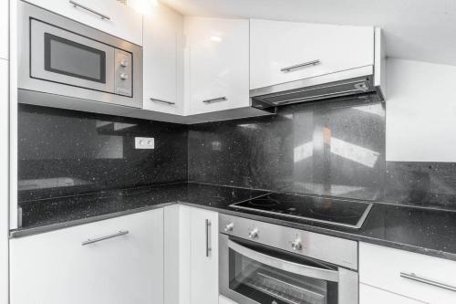 a kitchen with white cabinets and a stove and microwave at Precioso apartamento en Celorio, Llanes, Javier Bardon Treceno alquila in Celorio