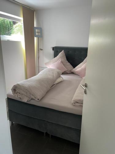 Una cama con almohadas rosas y blancas. en Brenzapartments Königsbronn 1 und 2, en Königsbronn