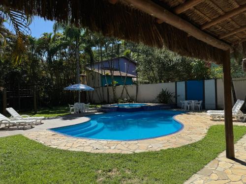 uma piscina com um pátio e um guarda-sol em Pousada Estrela do Mar em Maresias