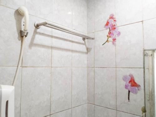 uma casa de banho com chuveiro com flores falsas na parede em Hotel Labuhan Raya em Medan