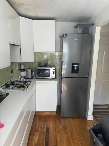 a kitchen with a stainless steel refrigerator and a microwave at 1 bed and breakfast by the Thames in Thamesmead