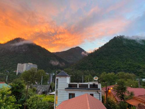 a building with a mountain in the background with a sunset at Guest house BORJOMULA in Borjomi