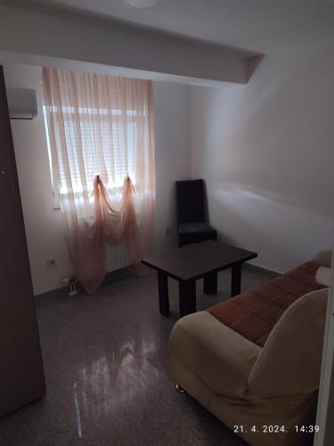 a bedroom with a bed and a window with a chair at Apartman in Vogošća