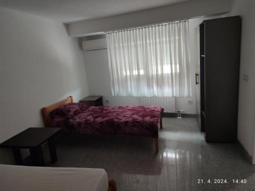 a bedroom with a bed and a window and a table at Apartman in Vogošća