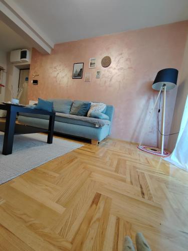 a living room with a blue couch and a wooden floor at Apartman_Krstić_1 in Subotica