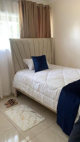 a bedroom with a white bed with a blue pillow at The Cozy Home in Nairobi