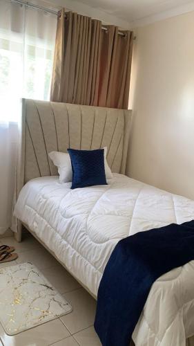 a bed with a blue pillow on top of it at The Cozy Home in Nairobi