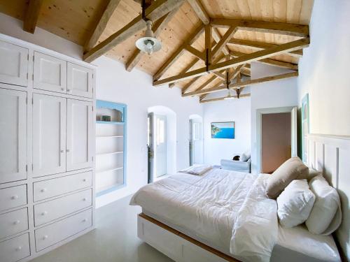 Hydra Homesteads في هيدرا: غرفة نوم بيضاء مع سرير كبير وسقوف خشبية