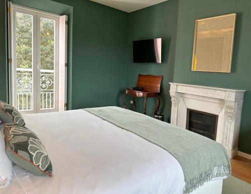 Dormitorio verde con cama y chimenea en Solar dos Cantos Botanic House & Garden, en Ponta Delgada