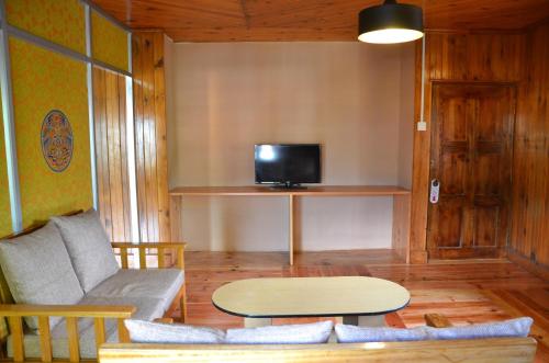 a living room with a couch and a table and a tv at Sinchula Villa in Paro