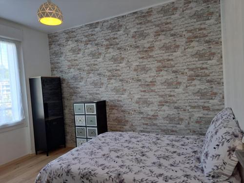 une chambre avec un lit et un mur de briques dans l'établissement Confortable Apart de 3 pièces, à Poitiers