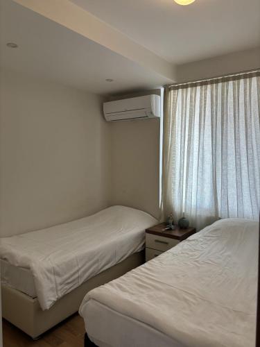 two beds in a small room with a window at Upart Home in Mersin