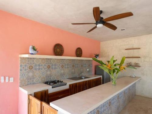 a kitchen with pink walls and a ceiling fan at María Amor- Contemporary Maya Oasis in Valladolid