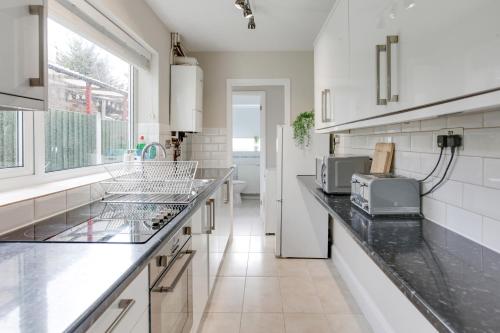 a kitchen with white cabinets and a counter top at Ann’s Place - 2 Bed House Central Romford - Free Parking & Garden in Romford