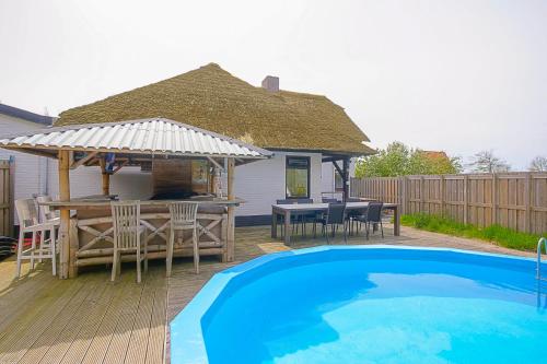 un patio trasero con mesa y una casa con piscina en Villa Pakhuys - groepsaccommodatie - Julianadorp aan Zee, en Den Helder