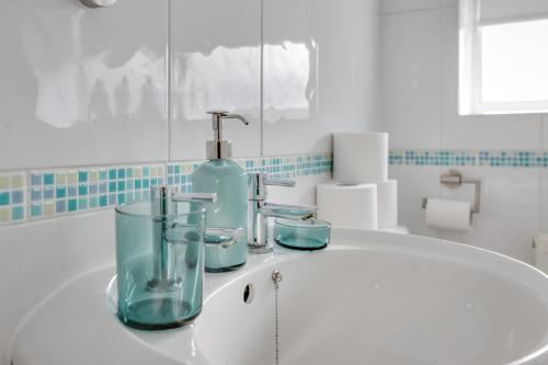 a bathroom sink with a bottle and glasses on it at Ann’s Place - 2 Bed House Central Romford - Free Parking & Garden in Romford