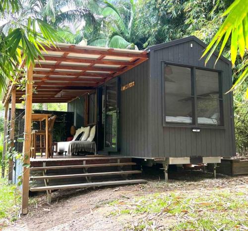 a black tiny house with a porch and a bed at Whispering Palms, Luxury Tiny Home in Crabbes Creek