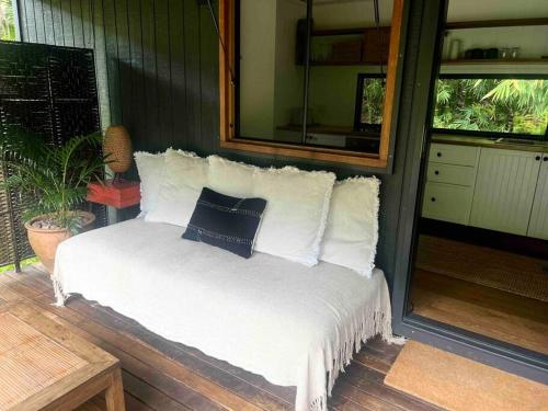 a bed with white pillows on a porch at Whispering Palms, Luxury Tiny Home in Crabbes Creek