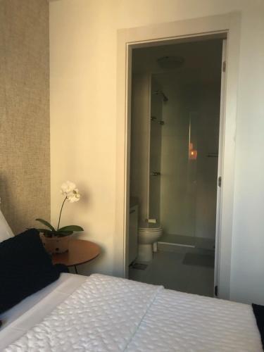 a bedroom with a bed and a bathroom with a toilet at Suíte Casal, RioCentro Parque Olímpico Barra da Tijuca in Rio de Janeiro