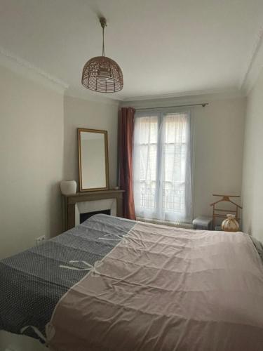 - une chambre avec un grand lit en face d'une fenêtre dans l'établissement Appartement parisien, à Paris