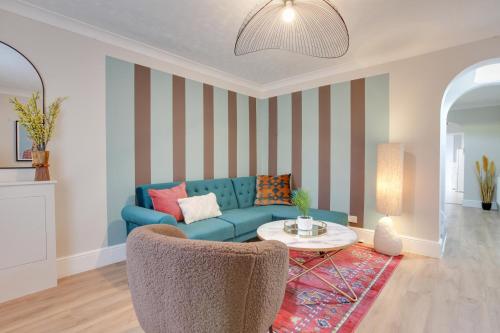 a living room with a blue couch and a table at Ann’s Place - 2 Bed House Central Romford - Free Parking & Garden in Romford