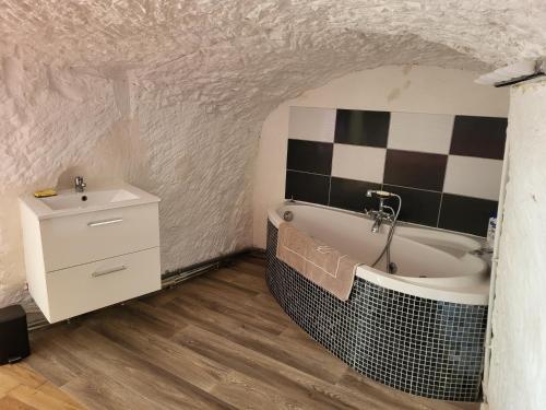 a bathroom with a bath tub and a sink at La grotte in Bourré