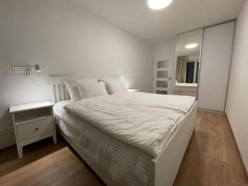 a white bedroom with a large bed and a mirror at Apartmán NAVIA obklopený prírodou a spa in Rajecké Teplice