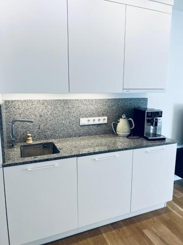 a kitchen with white cabinets and a sink at Tomy Old Town Apartments in Vilnius