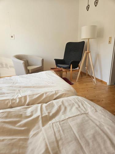 1 dormitorio con 1 cama, 1 silla y 1 lámpara en Ferienzimmer im Grünen, Privatunterkunft, en Dötlingen