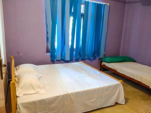 una camera con due letti e una finestra con tende blu di Inara Holiday Home a Anuradhapura