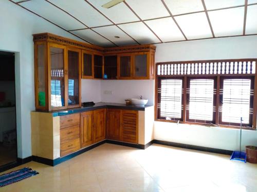 una cucina vuota con armadi in legno e finestre di Inara Holiday Home a Anuradhapura