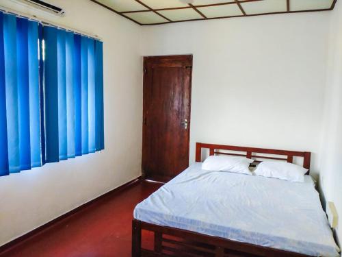 una camera con un letto e due tende blu di Inara Holiday Home a Anuradhapura