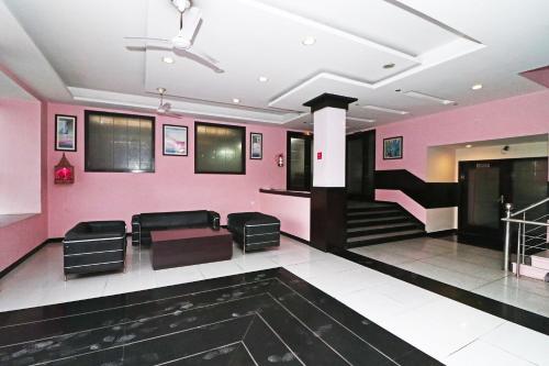una sala de espera con paredes rosas y sillas negras en SPOT ON Hotel Center Point, en Rāmpura