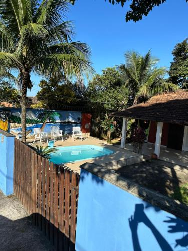 a swimming pool with a fence and palm trees at Aconchego da Vila in Mangaratiba