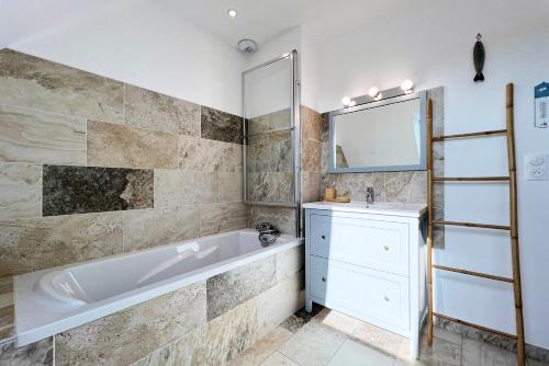 a bathroom with a tub and a sink and a mirror at Villa avec piscine privée, sauna, jardin et parking in Barneville-Carteret